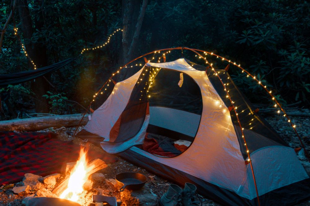 fairy lights on tent next to campfire